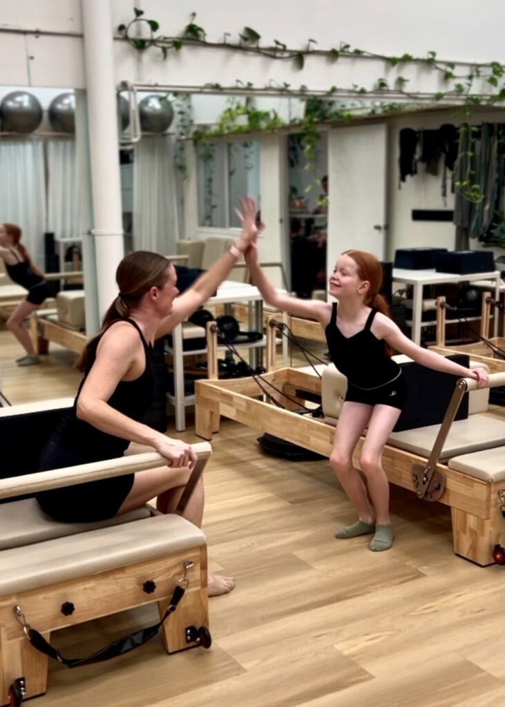 Mum and daughter giving high five after reformer pilates class